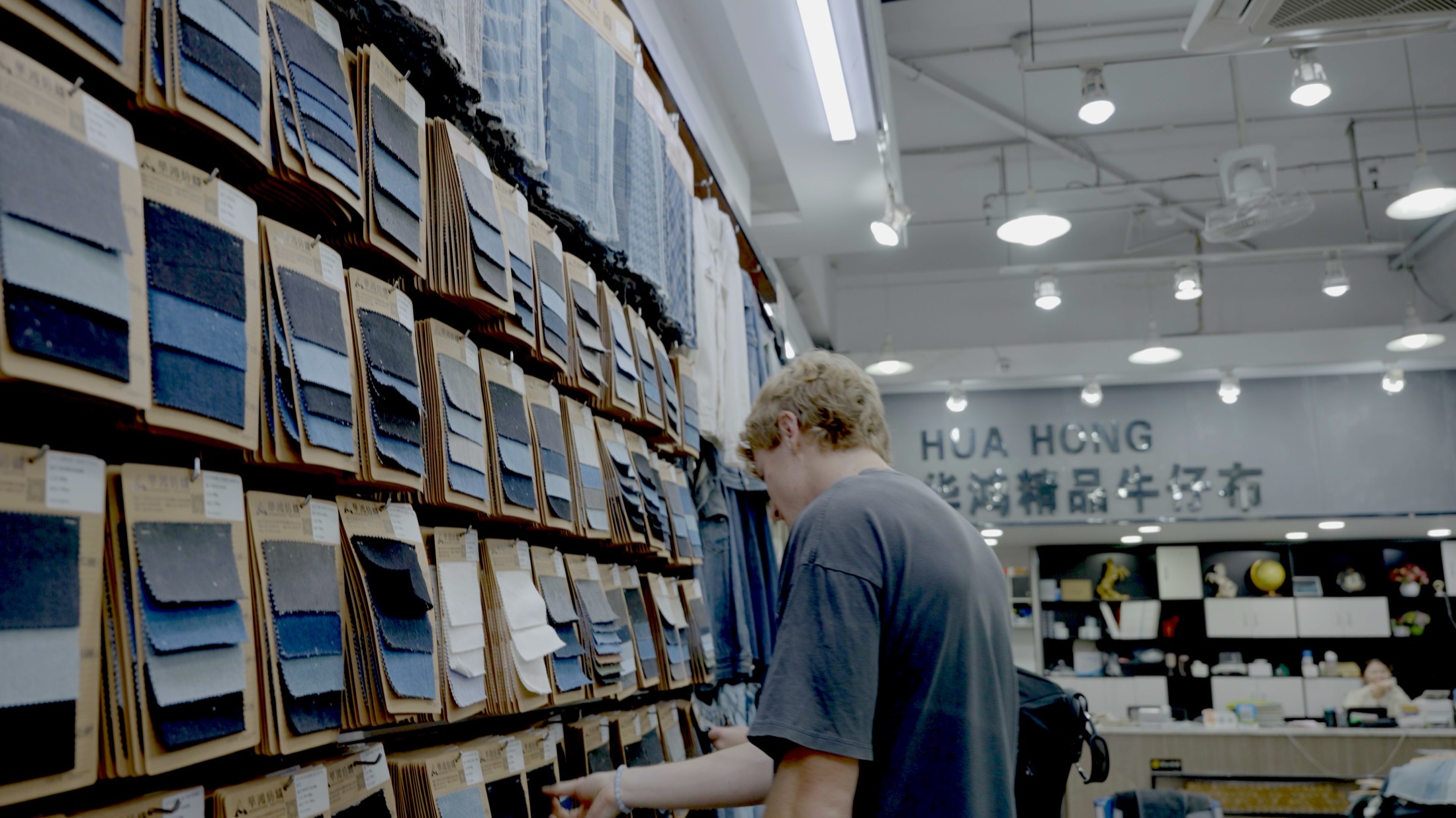 Browsing a floor-to-ceiling wall of denim swatch cards in a supplier showroom
